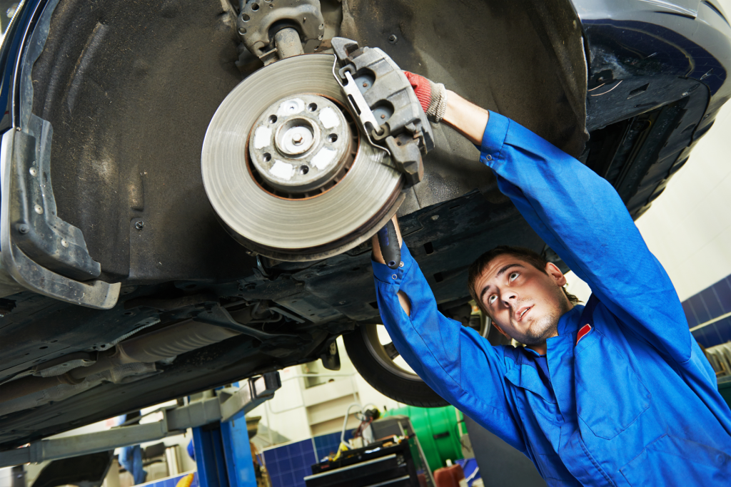 Mechanic inspecting and repairing car brakes